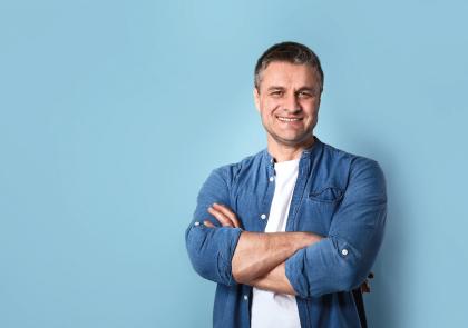 Een man met kort donker haar glimlacht naar de camera.